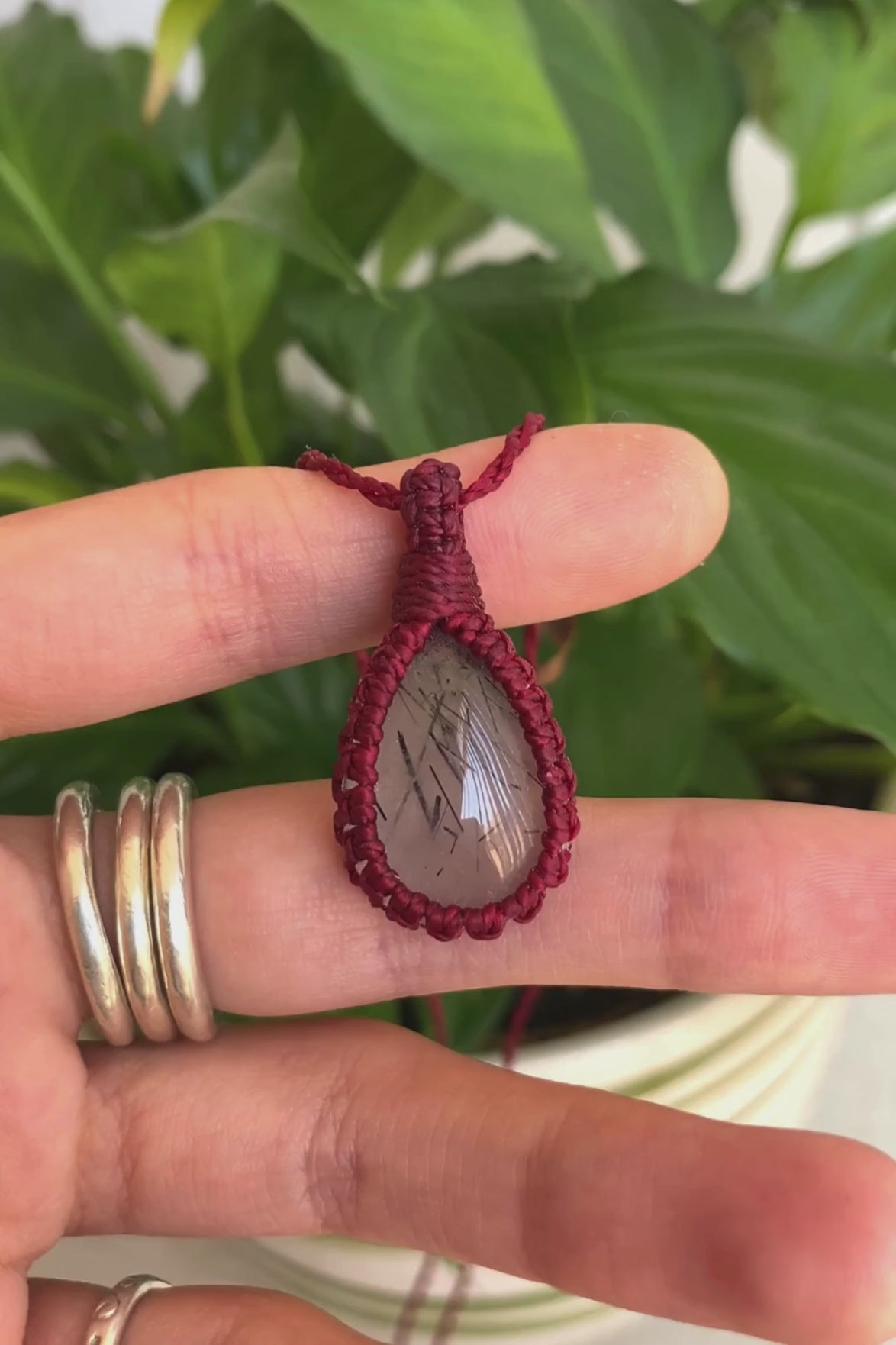 Video of a handmade Tourmaline Quartz macrame necklace, highlighting the gemstone’s black tourmaline inclusions, red macrame details, and how it catches the light.