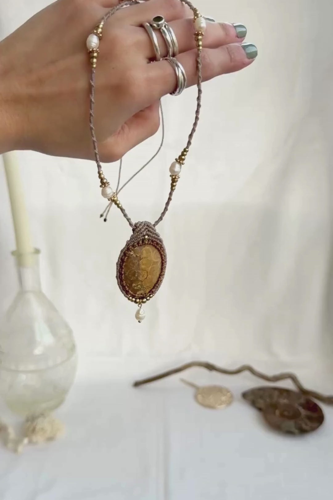 Video showing fossil coral pendant necklace with freshwater pearl drop, pearls along macramé cord, and detailed craftsmanship