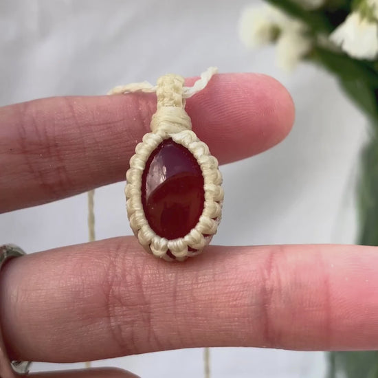 Video of a handmade Carnelian macrame necklace, capturing the gemstone’s fiery red glow and the intricate macrame knotting in detail.