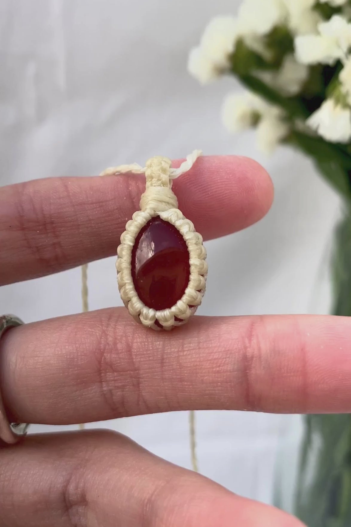 Video of a handmade Carnelian macrame necklace, capturing the gemstone’s fiery red glow and the intricate macrame knotting in detail.