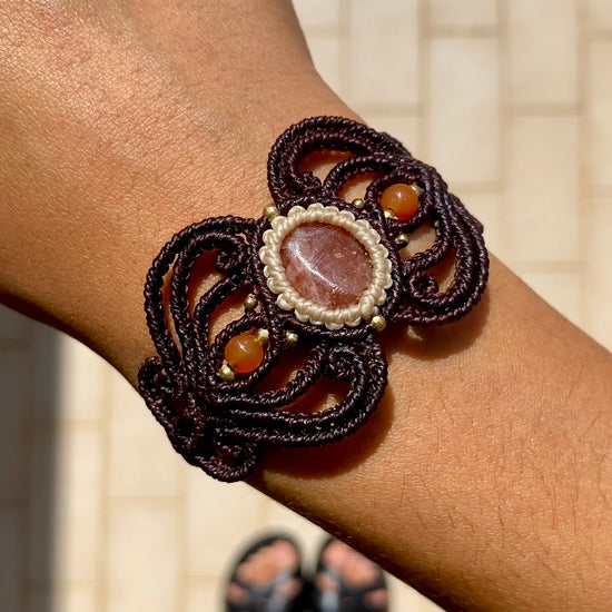 Close-up video of the handmade bracelet, capturing the shimmer of the Sunstone and the brilliance of the carnelian accents, highlighting the unique craftsmanship and quality of the design.